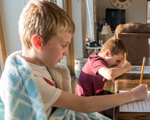 Photo of two boys sitting at a table doing homework